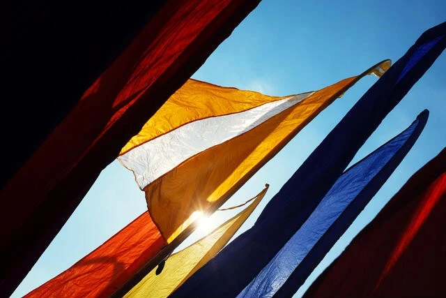 Vibrant yellow and white Bali banners waving under blue sky for festive outdoor advertising.