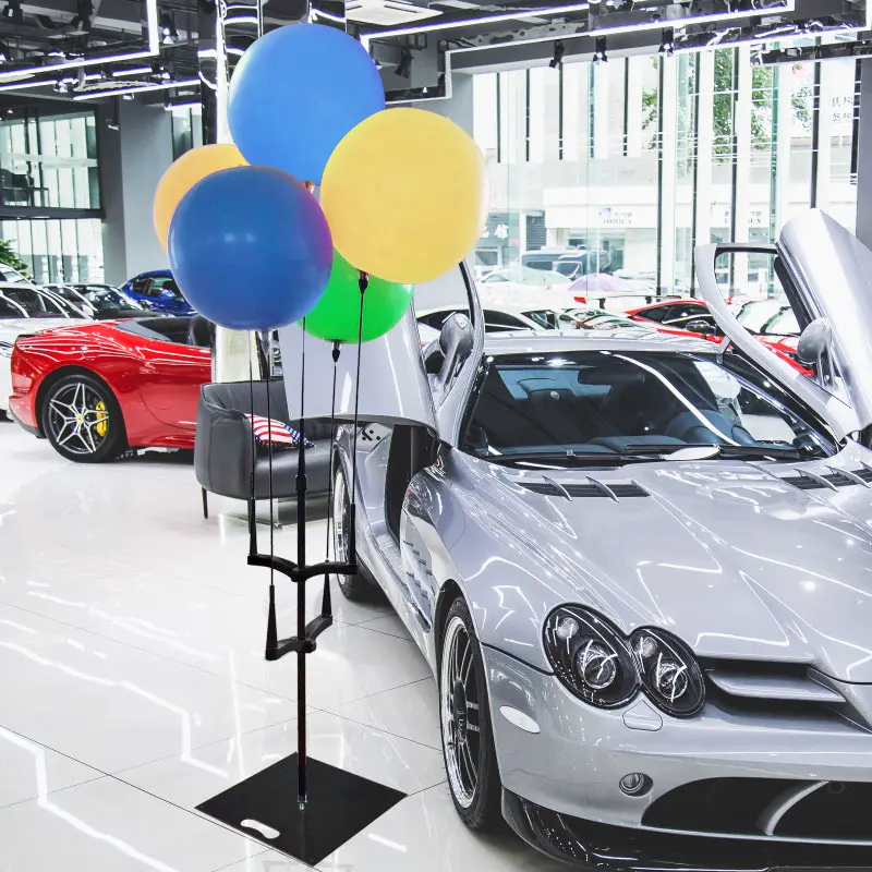 Car dealership marketing application: A silver sports car accompanied by a Cluster Balloon Kit in a modern showroom, demonstrating high-visibility retail advertising.