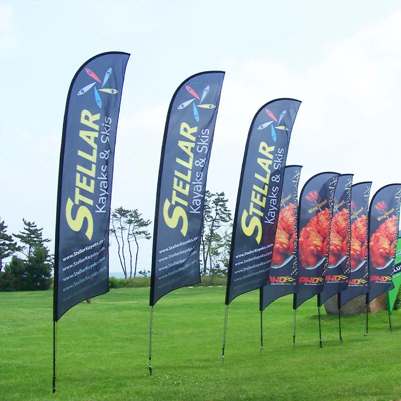Multiple navy blue blade feather flags in grassy field displaying