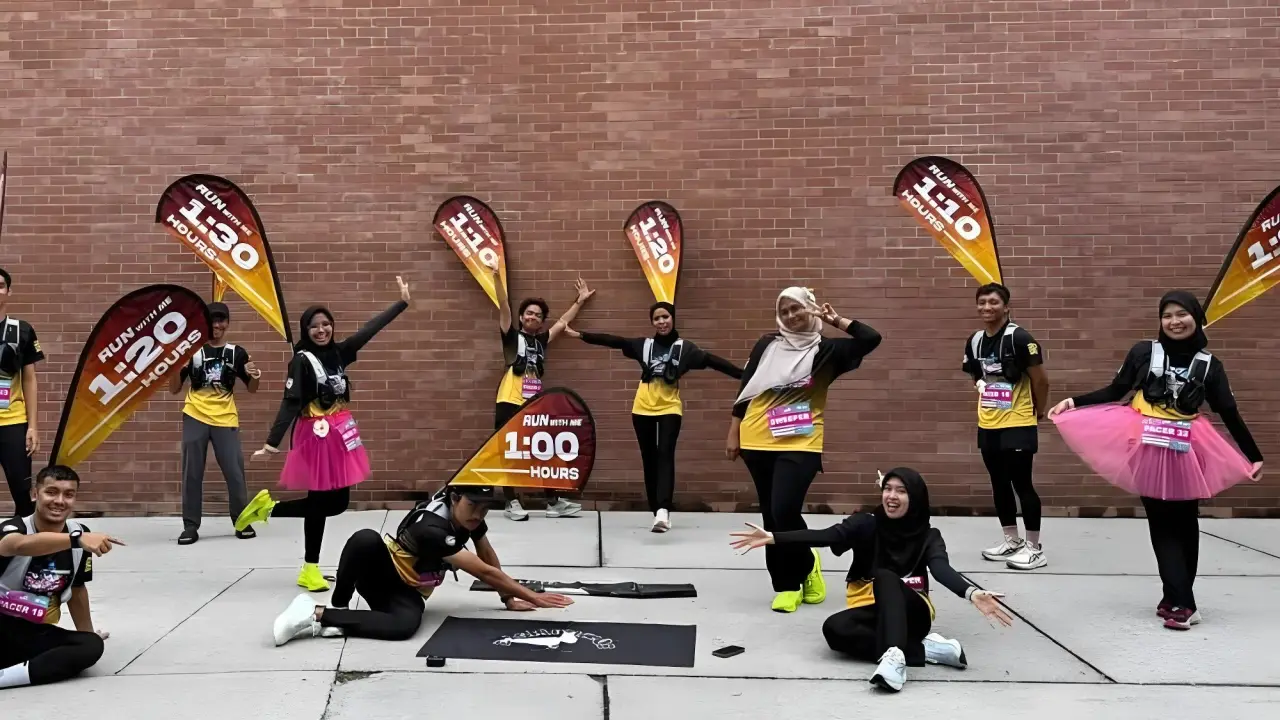 Energetic team of marathon pacers posing with their RUN WITH ME teardrop flags and matching pacer backpacks.