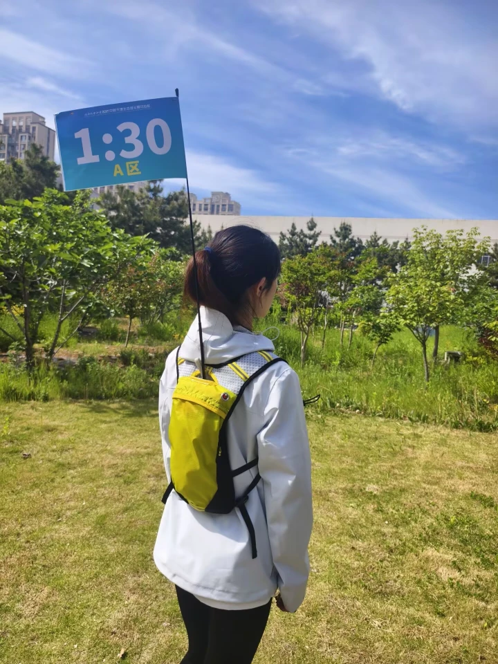 WZRODS neon marathon pacer backpack with 'Zone A 1:30' teardrop flag at race start