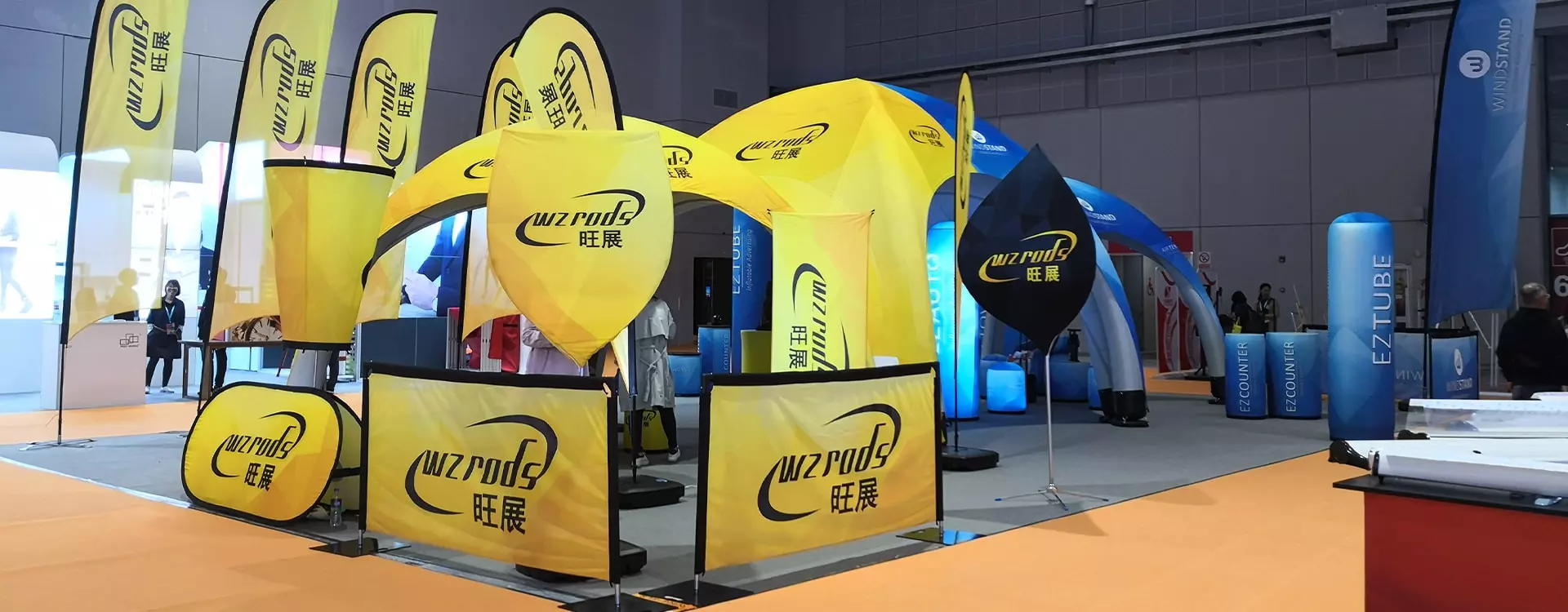 Weihai WZRODS trade show booth with yellow WZRODSdoor frame/cafe barrier displaysWZRODS, WZRODSCurved BannersWZRODS, and inflatable arches. Features bold flags.
