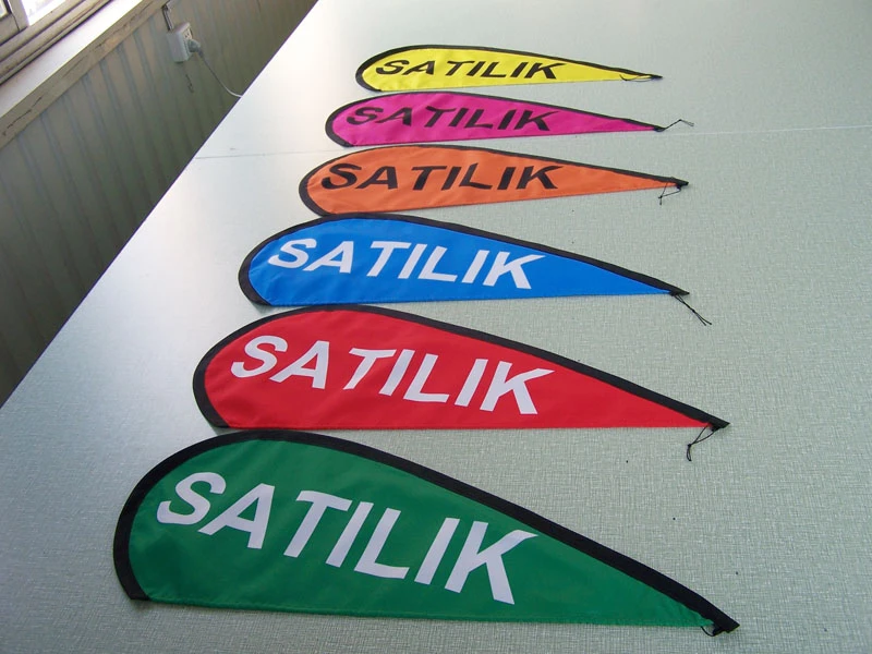 Rainbow teardrop flags with white 'SATILIK' text on striped wall.