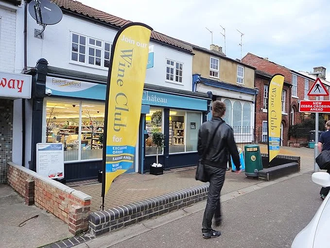 Château wine shop with yellow 'Wine Club' feather flags on UK high street, East Anglia signage, blue-white building