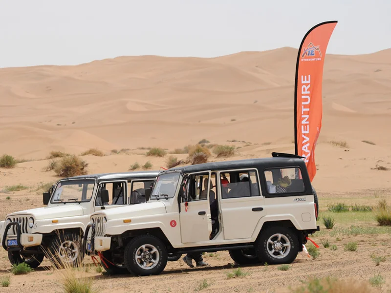 White off-road SUVs in desert with orange razor flag 'ADVENTURE', rugged outdoor branding.