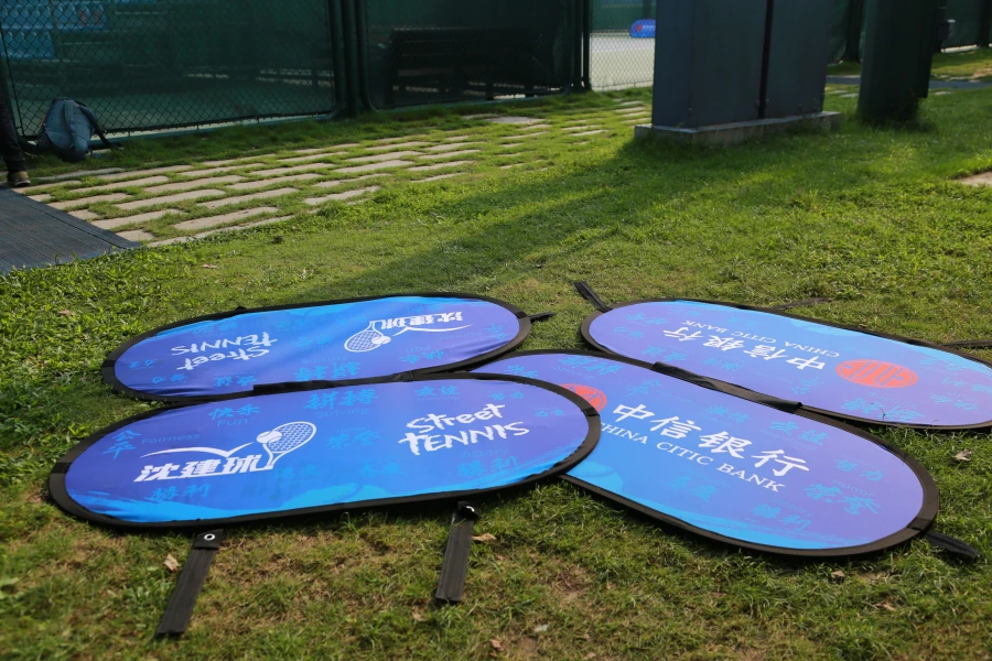 Blue sideline banners ('Street Tennis,' China Citic Bank) lying on grass, prepared for installation at a sports event.