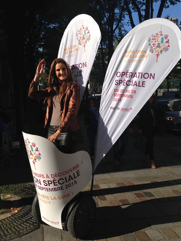 Branded teardrop flags at a Paris Open event, promoting a Mid-Autumn Festival special with a smiling brand ambassador.